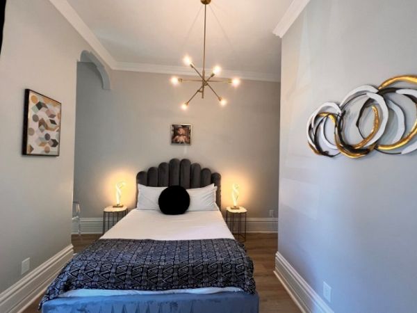 A modern bedroom with a centered bed, decorative wall art, and a stylish chandelier.